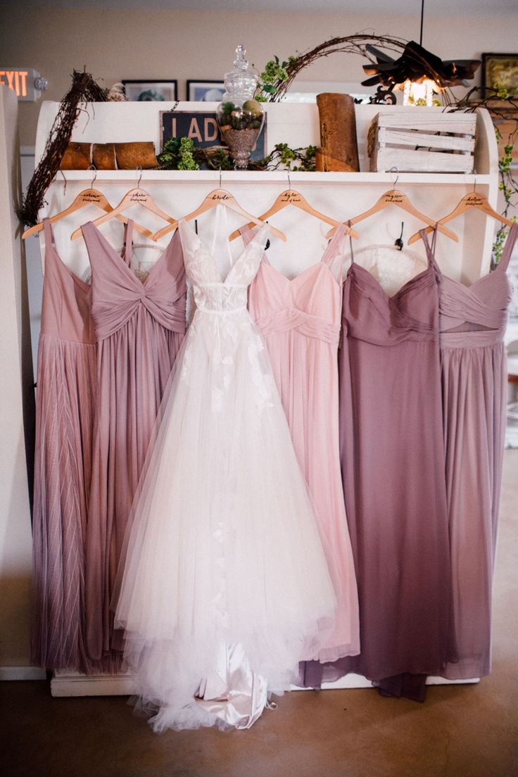 four bridesmaid dresses hanging on a rack in the bridal room at a wedding