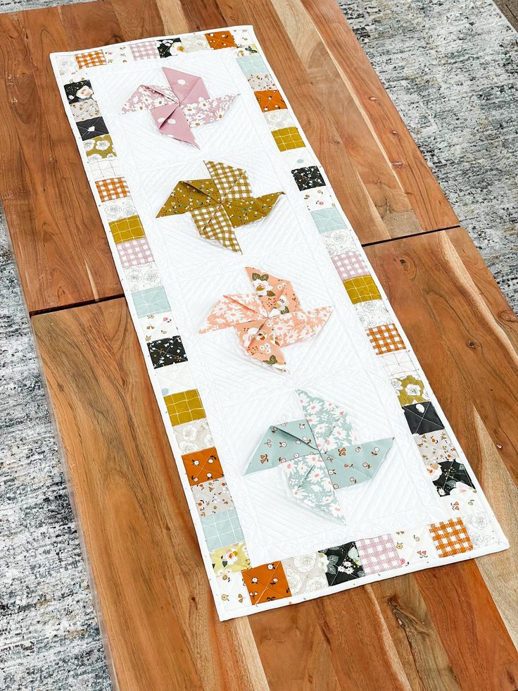 a table runner made out of scrap paper and fabric on top of a wooden floor