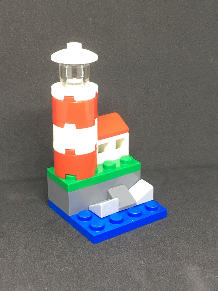 a lego lighthouse made out of blocks on top of a gray surface with blue and white trim