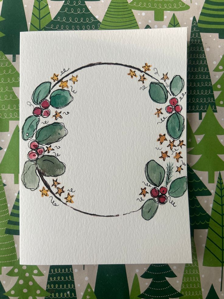 a white card with green leaves and berries on it, surrounded by evergreen trees in the background