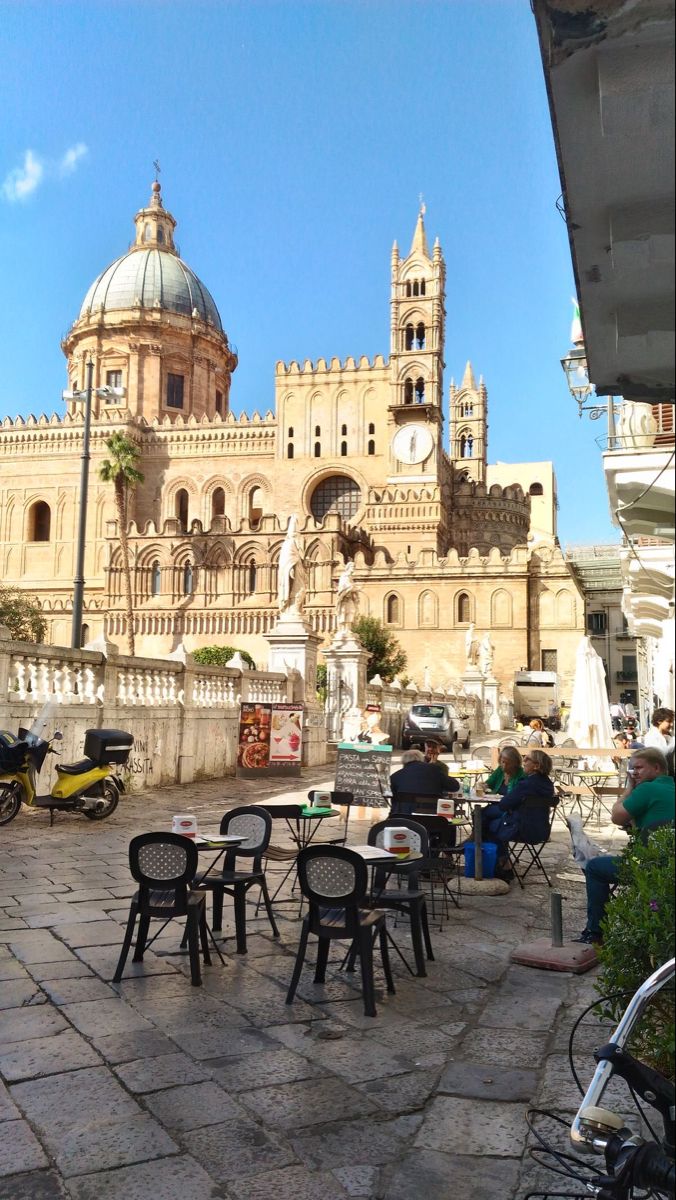 people sitting at tables in front of an old building