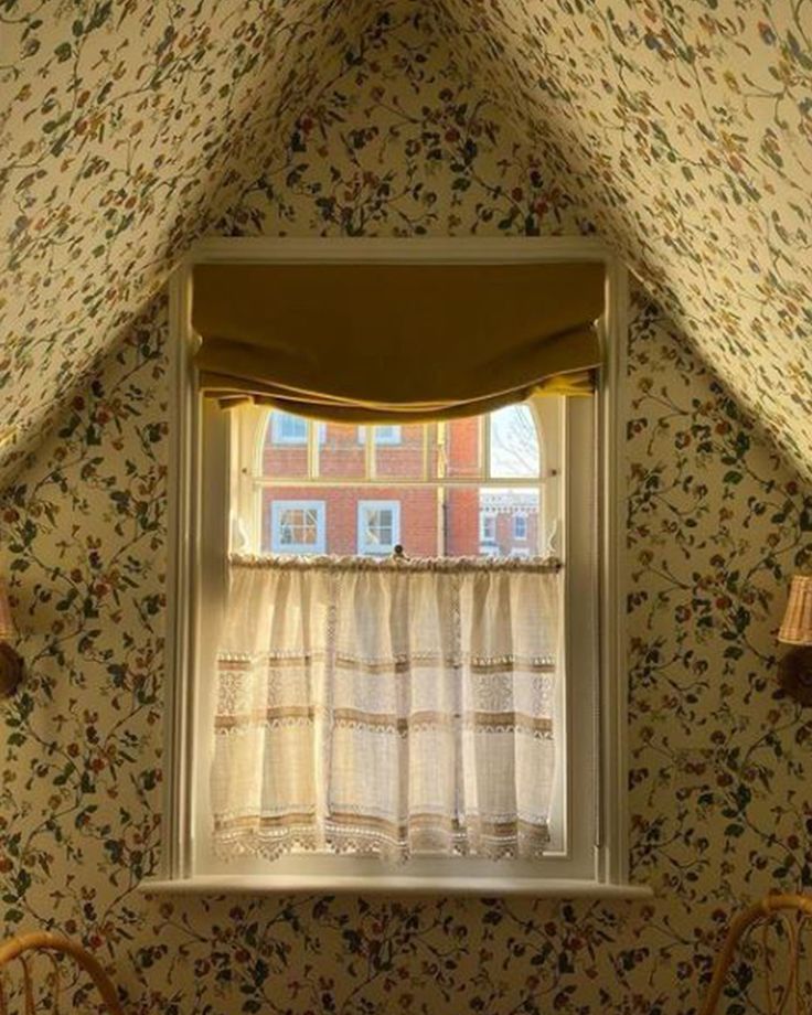 a window in the corner of a room with floral wallpaper and curtains on it