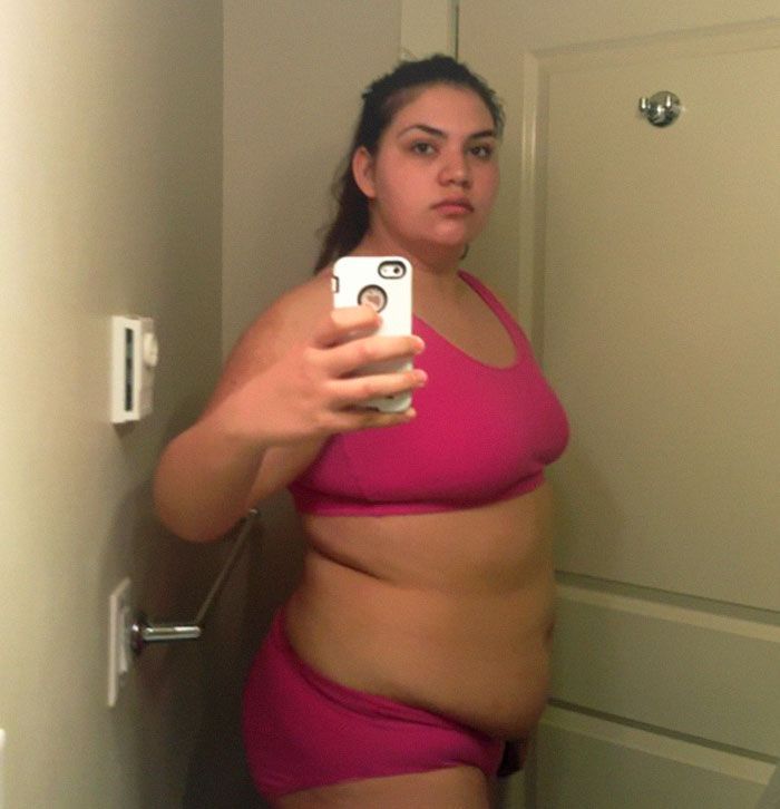 a woman taking a selfie in a bathroom mirror while wearing a pink bathing suit