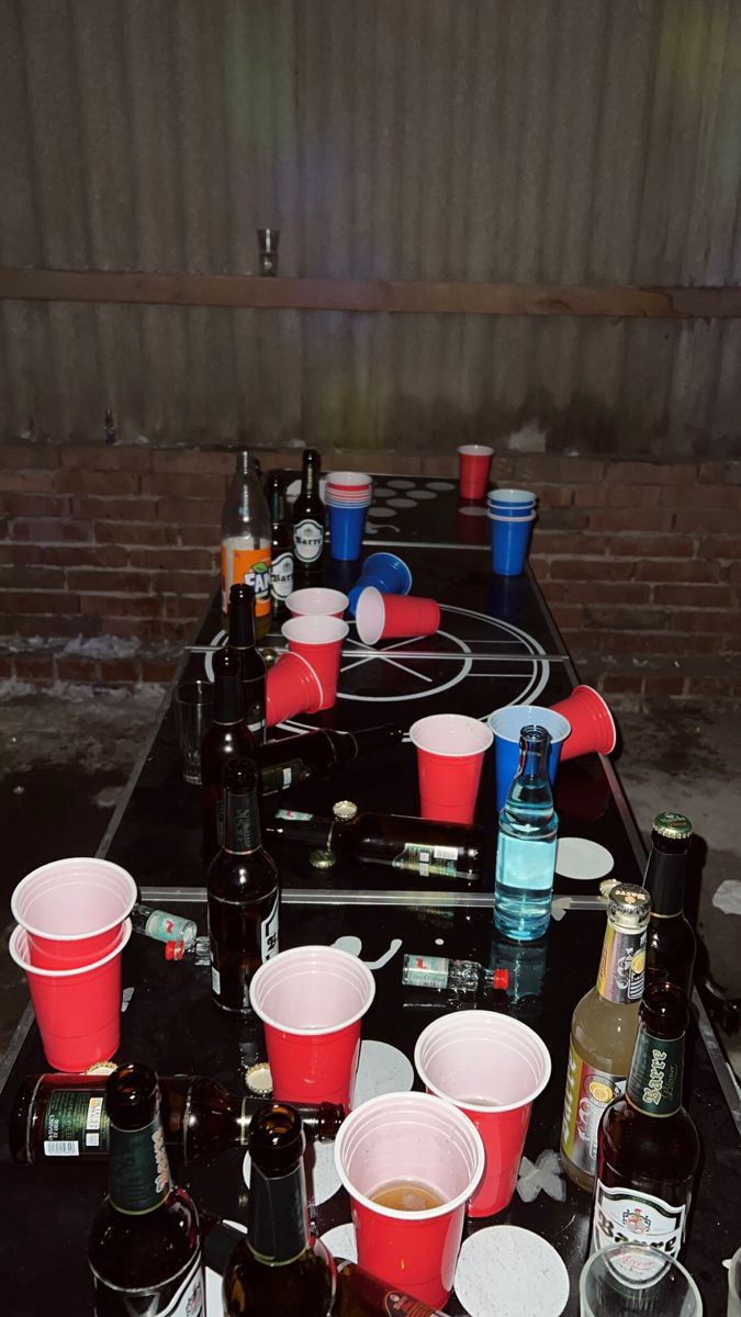 a table topped with lots of cups filled with drinks next to bottles and glasses on top of it