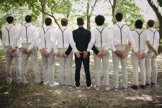 a man standing in front of a group of men wearing white pants and suspenders