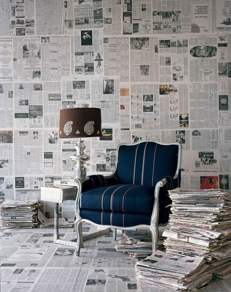 a blue chair sitting in front of a pile of newspapers