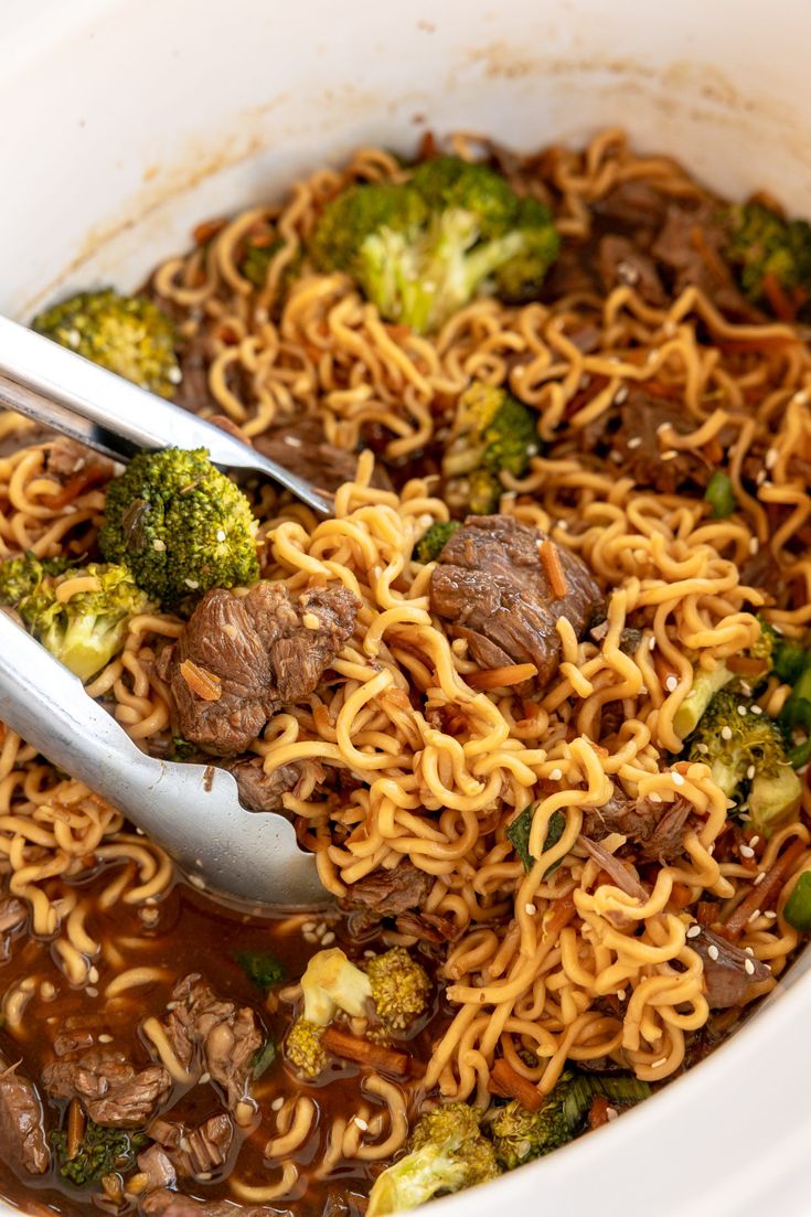 a close up of a bowl of noodles with broccoli and beef in it