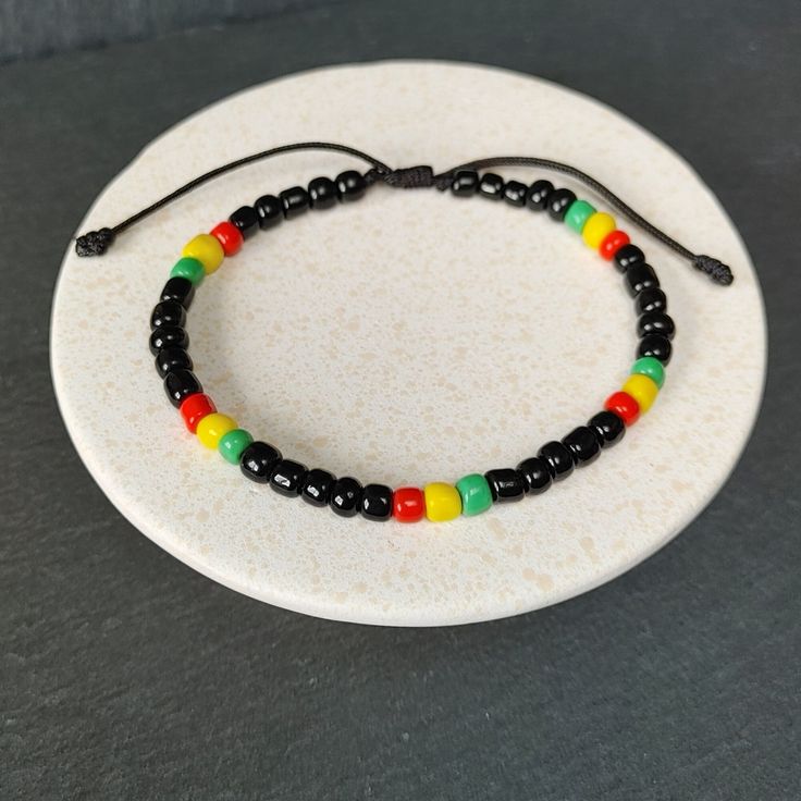 Rastafarian Seed Beads Bracelet, Adjustable Jamaican Bob Marley Style, Reggae Red, Yellow, Green, Black | Unisex Gift | Rastafari Vibes, One Love, Handmade Gift for Her and Him Rasta Bracelet - Radiate the Reggae Spirit! Handmade with a celebration of Rastafari Seed Beads in Jamaican Bob Marley Style. Capturing the Red, Yellow, Green, and Black essence of Reggae, this unisex bracelet is a unique gift for all. Handcrafted Details: Authentic Rastafarian Design: Representing unity, love and positiv Bob Marley Bracelet, Black Resizable Bracelet For Festivals, Black Resizable Bracelet For Festival, Black Round Beads Bohemian Friendship Bracelets, Black Bohemian Friendship Bracelets With Round Beads, Adjustable Black Bohemian Beaded Bracelets, Black Round Bead Bracelets For Festival, Black Round Beads Friendship Bracelets With Adjustable Length, Black Round Beads Bracelet For Festival