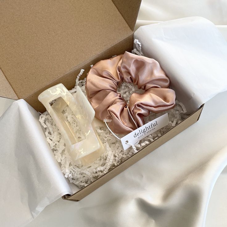 an open box with two scrunffles and a soap in it on a white sheet