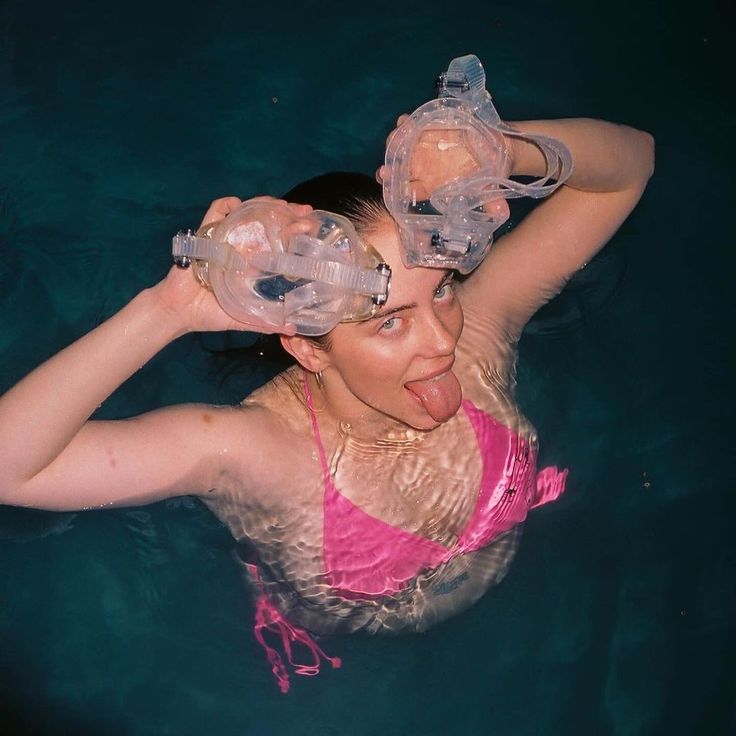 a woman floating in the water wearing goggles and snorkels on her head