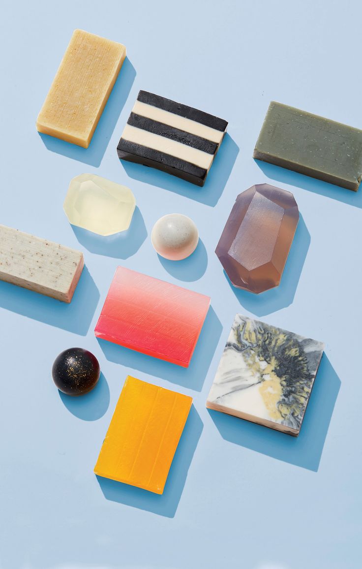 several different types of soaps on a blue surface with black and white objects around them