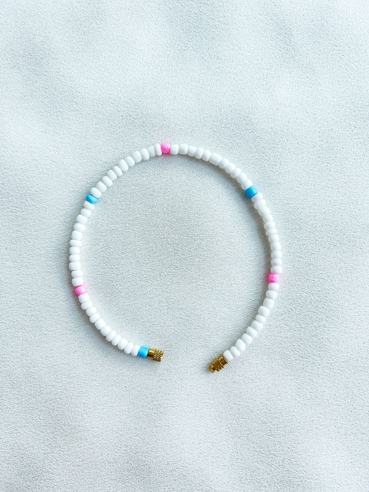 Handcrafted white beaded anklet/bracelet with pink and blue details. Made using large colourful round glass beads and finished with a gold-plated barrel clasp closure. Pair it with our matching Necklace.  * Weight: 7g   * Width: 5mm/2mm  * Made in UK  * Code: 111AWPBL The very best in unique, handmade pieces from BAM-BAM, our anklets and bracelets make great accessories for the beach, festival or club. These large beads have a bold appearance and can take your best looks from day to night. White Beaded Anklets For Summer, White Letter Beads Bracelets For Beach, White Bracelets With Letter Beads For Vacation, White Bracelet With Letter Beads For Vacation, White Letter Beads Bracelet For Vacation, White Jewelry With Letter Beads For Vacation, White Round Bead Bracelets For Vacation, White Round Beads Bracelets For Vacation, White Heishi Beads Strand Necklace