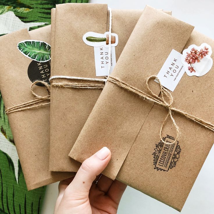 three brown paper packages tied with twine and string, one being held by a person's hand