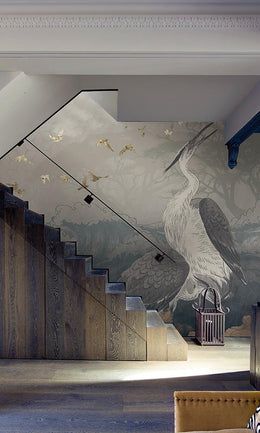 a large bird painted on the side of a wall next to a stair case in a living room