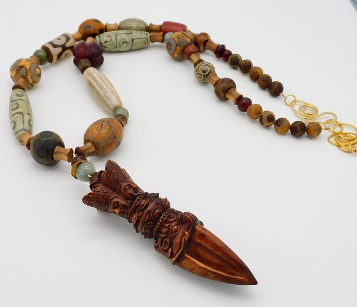 This long, flattering length necklace features an extraordinary handcarved vintage Tibetan boxwood amulet....the workmanship is wonderful!  Amulet is approximately 3 3//4 inches in height and I have topped it with a jade and horn bead.  Amulet hangs from long necklace made of a plethora of stunning handcarved beads....including etched and handpainted Tibetan agate in various shapes, sizes and colors, jade, gorgeous handcarved high-quality horn beads, handcarved wooden spacer beads from Vietnam and handmade Mprccan bead. Necklace fastens with my signature, large fancy handmade brass clasp and high-quality 18KT matte gold over brass chain.  Chain is tarnish-resistant.   Length adjusts from about 27 -29 inches. Brown Carved Amulet Necklaces, Artisan Carved Necklace For Collectors, Artisan Carved Necklace Collectible, Carved Beaded Necklaces For Spiritual Gifts, Brown Carved Spiritual Jewelry, Spiritual Brown Carved Jewelry, Unique Carved Brown Necklace, Unique Brown Carved Necklace, Traditional Brown Carved Jewelry