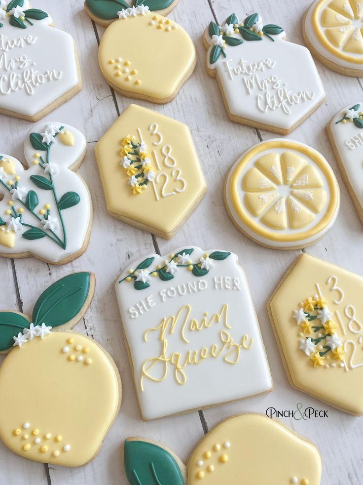 some decorated cookies are sitting on a white wooden table with green leaves and lemons