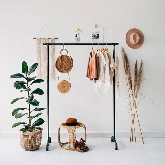 a white room with plants, hats and clothes hanging on the rack next to it