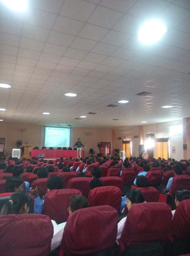 an auditorium full of people in red chairs