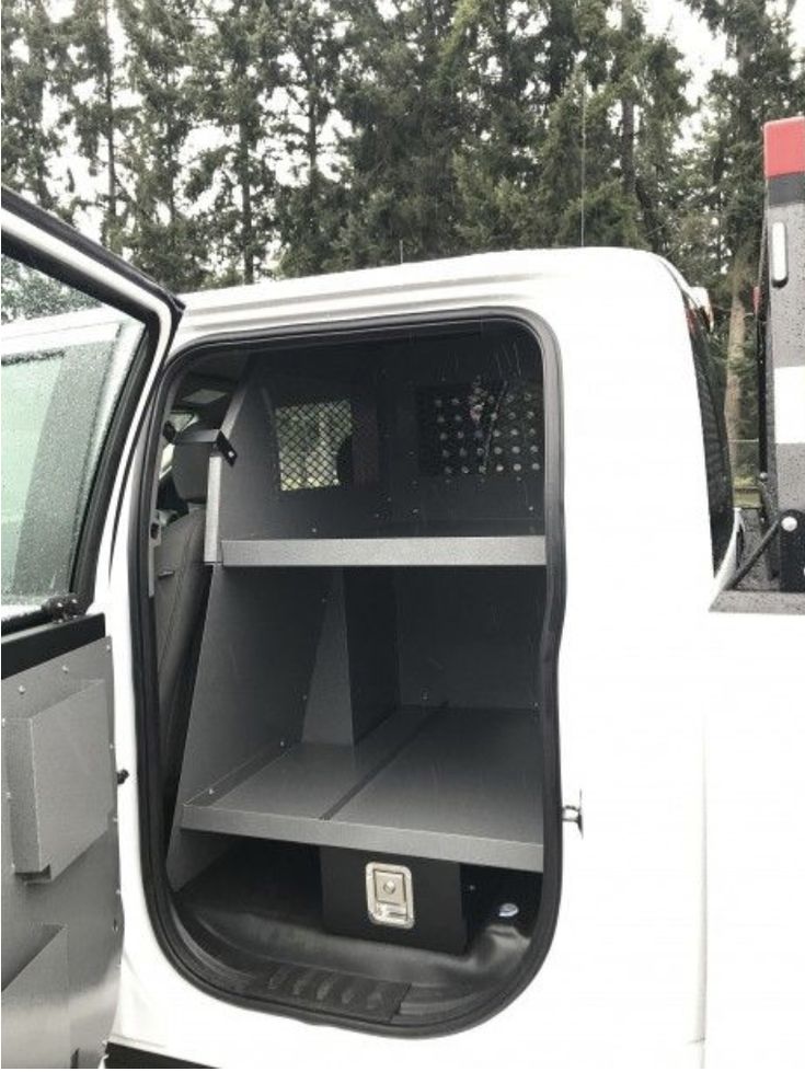 the back end of a white truck with its doors open and shelves in the side