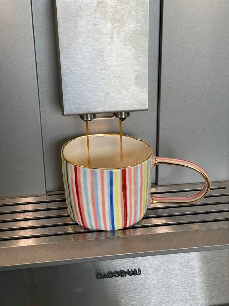 coffee being poured into a colorful striped cup