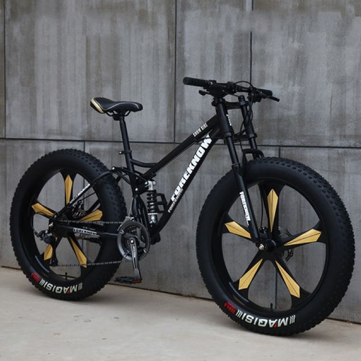 a bike parked next to a wall with yellow and black spokes on the front wheel