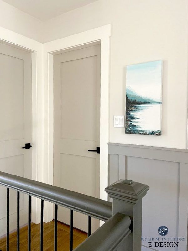 an empty hallway with white walls and black railings, along with two paintings on the wall