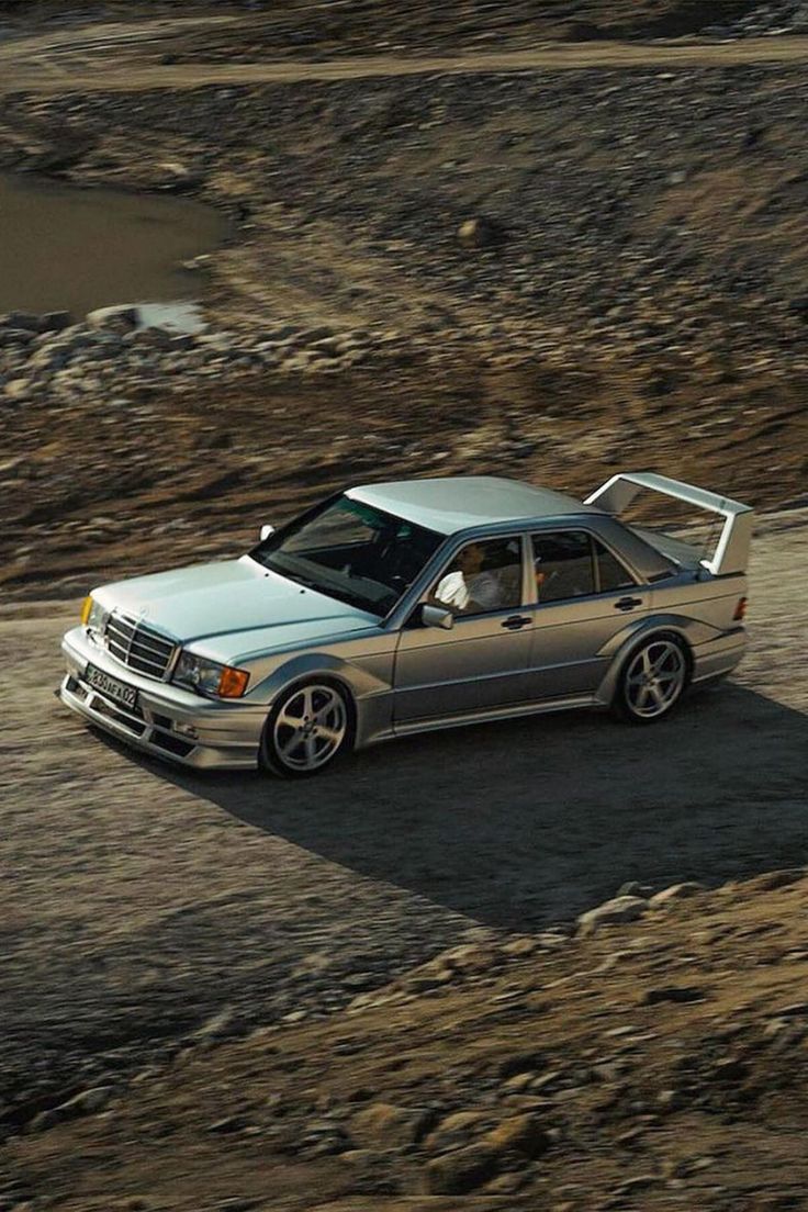 a silver car driving down a dirt road