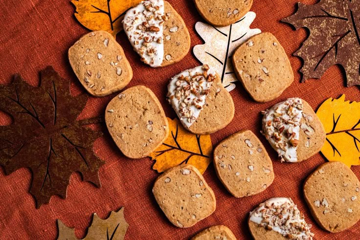 several cookies are arranged on a table with autumn leaves and maple leaves in the background