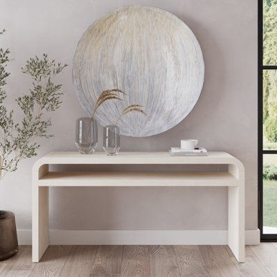 a white table with vases and plants on it next to a large round painting