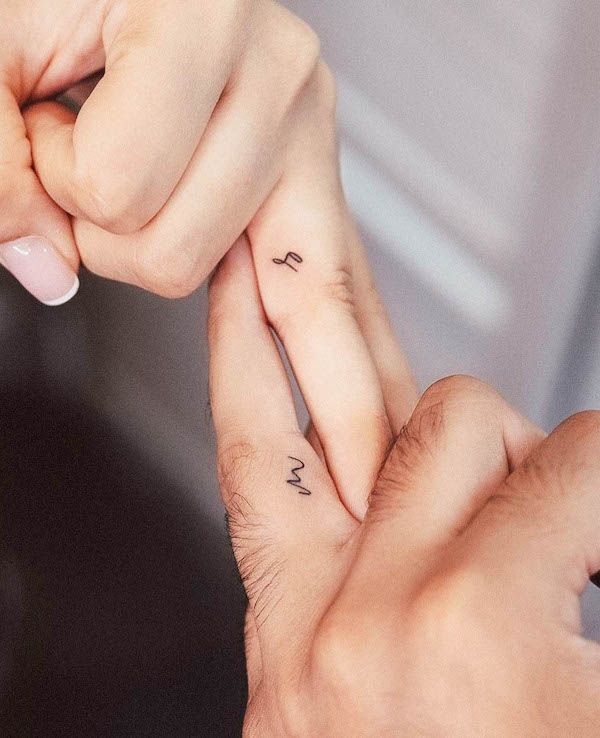 two people holding hands with small tattoos on them