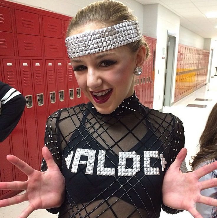 a woman in a black and silver outfit with her hands out to the side while standing next to lockers