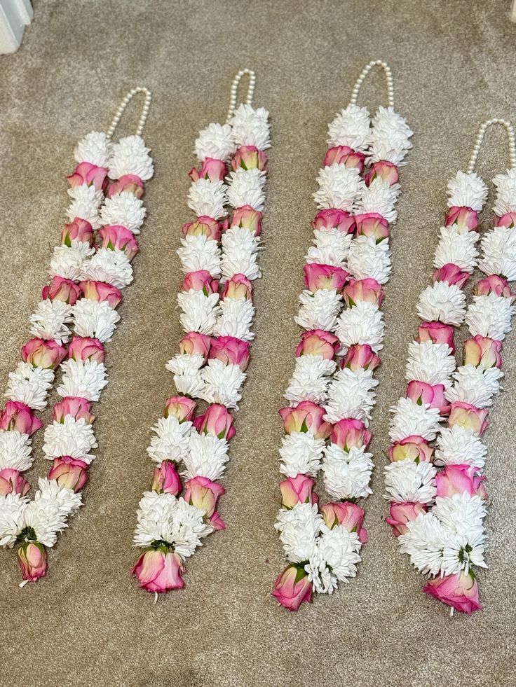 four pieces of pink and white flowers on the floor next to each other with pearls hanging from them