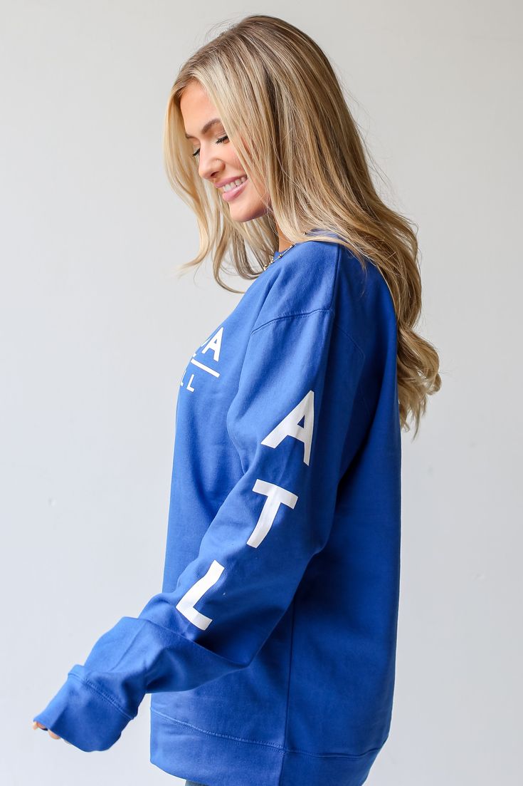 a woman wearing a blue sweatshirt with white letters on it