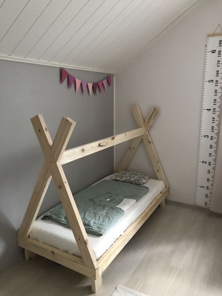 a wooden bed frame in the corner of a room with a ruler on the wall