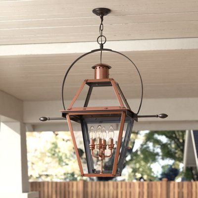 an outdoor light hanging from the ceiling in front of a wooden fenced porch area