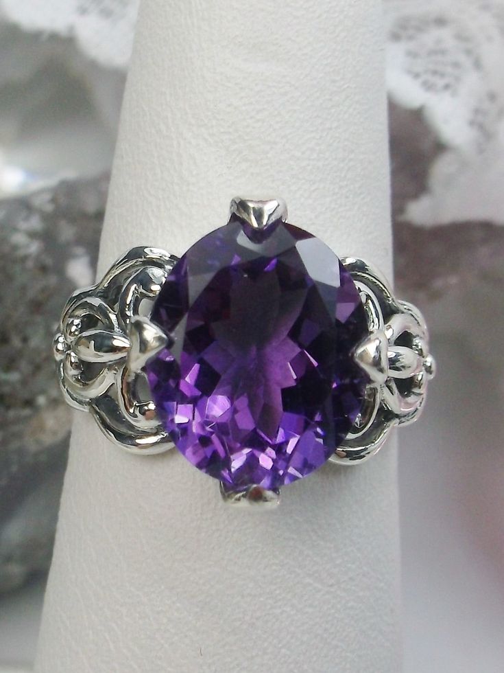 Natural Purple Amethyst RingSmall Fat Oval Design#D111 Inspired by Gothic designs, this stunning antique reproduction ring is crafted in sterling silver. This gorgeous ring is set with a flawless oval-cut natural purple amethyst. The stunning 3 carat weight gemstone is 11mm x 9mm. The band is marked 925 for sterling silver. Notice the beautiful silver filigree swirl setting and band. The bold style travels around the base of the gem and morphs into a solid band. The stunning gem rises above the Elegant Purple Amethyst Ring Oval Cabochon, Elegant Purple Oval Cabochon Amethyst Ring, Classic Oval Amethyst Ring, Victorian Style Oval Purple Amethyst Ring, Victorian Style Purple Oval Amethyst Ring, Silver Amethyst Ring With Intricate Design, Elegant Amethyst Oval Cabochon Ring, Oval Sterling Silver Amethyst Ring With Intricate Design, Oval Amethyst Ring In Sterling Silver With Intricate Design