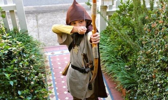 a young boy dressed in costume holding a stick