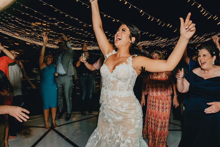 a woman in a wedding dress dancing on the dance floor with her arms raised up