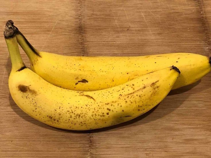 two bananas sitting on top of a wooden table