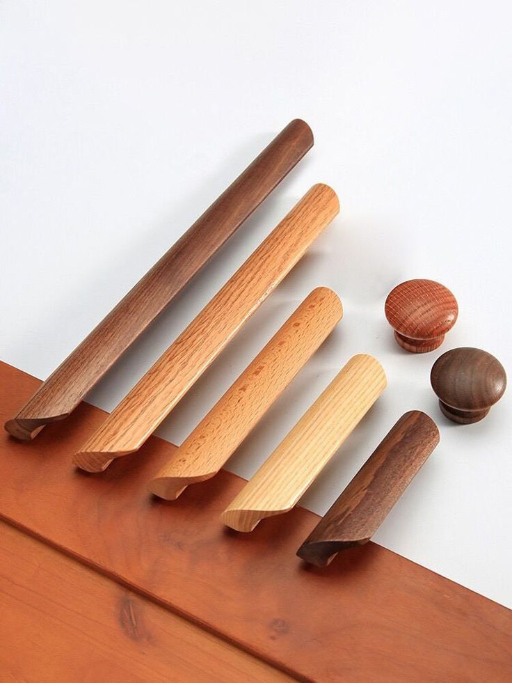 five wooden spoons and two seashells on a white surface with wood grain