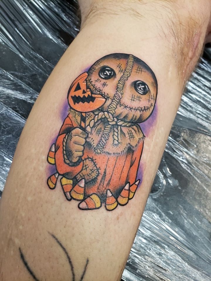 a person with a tattoo on their arm holding an orange jack - o - lantern