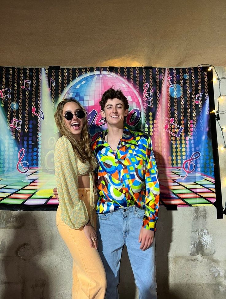 a man and woman standing next to each other in front of a wall with disco lights