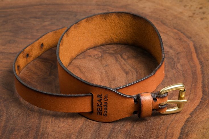 a brown leather belt sitting on top of a wooden table