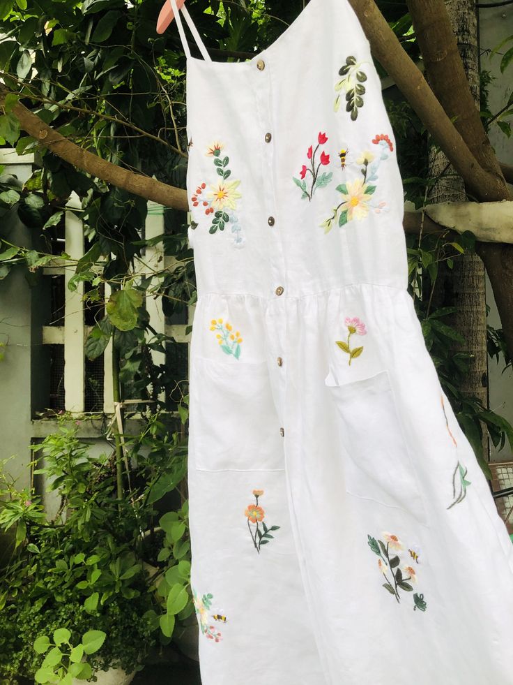 ❤ The white linen hand embroidered dress is very soft, skin friendly, breezy and comfortable. ❤ Item description: - A lovely dress with colourful embroidered wild flowers and bee motifs. You seem to be lost in a garden which full of fragrant flowers and strange grass. - Material: linen, coconut button, embroidery threads. - Environmentally friendly. - This dress is very useful, go with any outfit, that can be used to go to school, go out, go shopping. It is a perfect gift for yourself or your be Embroidered Flower Dress For Summer, Summer Floral Applique Embroidered Dress For Garden Party, Multicolor Floral Embroidered Dress For Garden Party, White Floral Embroidery Dress For Garden Party, White Linen Dress For Summer Garden Party, Spring Floral Embroidered Sundress For Garden Party, Cottagecore Embroidered Dress For Garden Party, Casual Floral Embroidered Dress For Garden Party, Floral Embroidered Sundress For Spring Garden Party