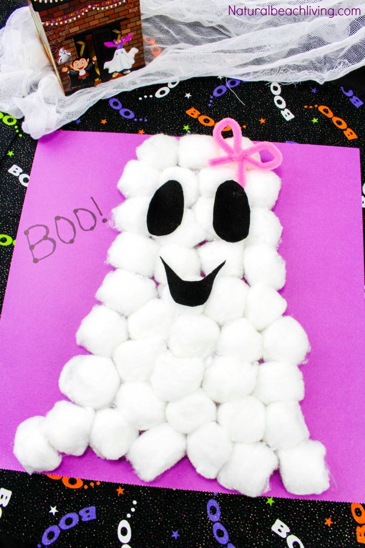 marshmallow ghost craft for kids to make on the table with halloween decorations in the background