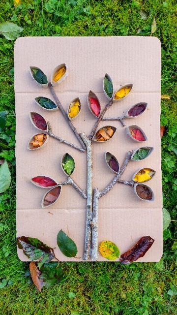 a tree made out of leaves sitting on top of a piece of cardboard in the grass