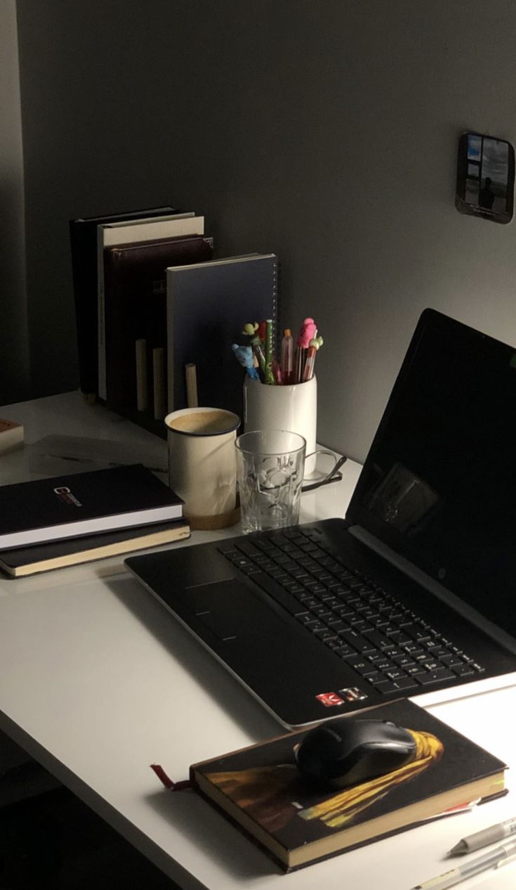 an open laptop computer sitting on top of a desk next to a mouse and books