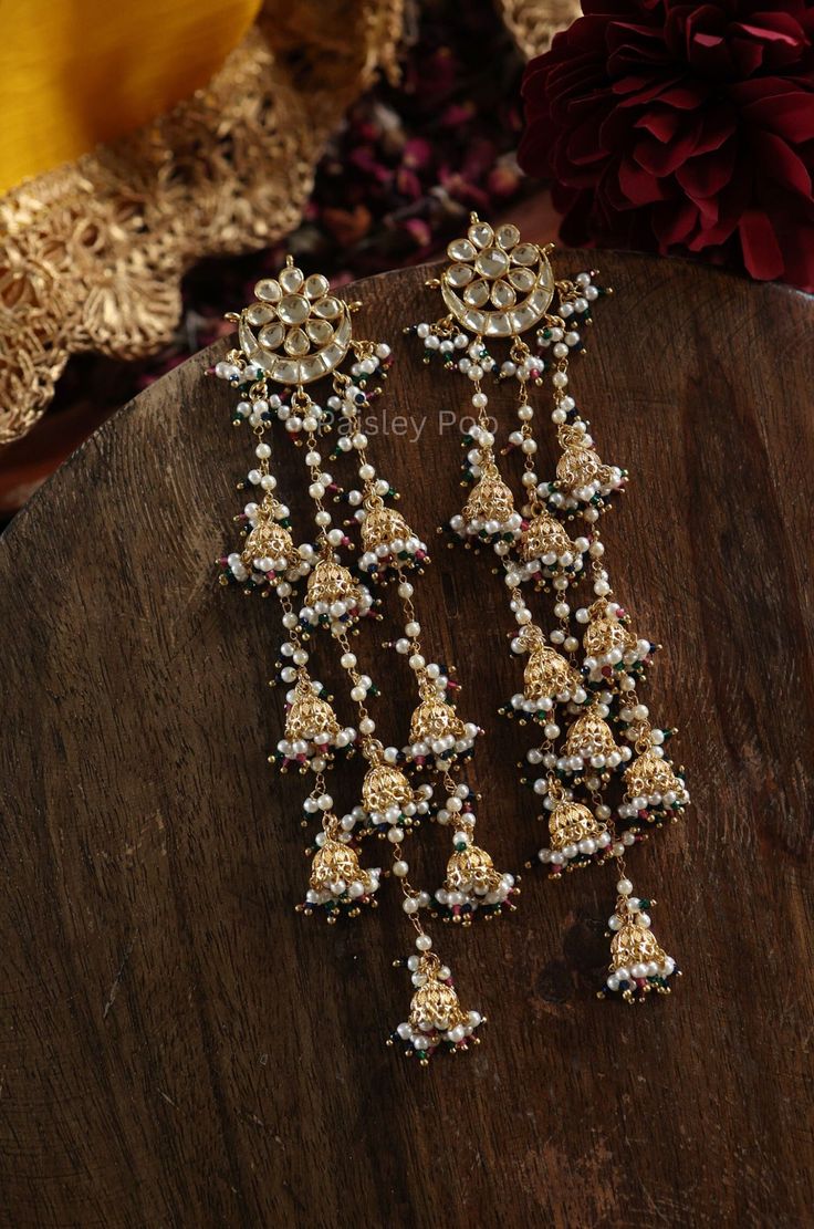 Experience the beauty of blooming flowers with these floral kundan earrings. Adorned with delicate jhumkis of elegance and highlighted by pearls and green hydro stones, these earrings exude impeccable craftsmanship and divine allure. Perfect for adding a touch of grace and purity to any outfit. Closure - Push Back Fusion Kundan Jhumkas Drop Earrings, Kundan Fusion Jhumkas, Fusion Style Kundan Jhumkas, White Jhumkas For Reception And Festivals, White Meenakari Jhumkas For Reception, Festive Tilla Danglers For Reception, Kundan Fusion Dangle Jhumkas, Fusion Style Kundan Dangle Jhumkas, Meenakari Drop Earrings Jhumkas For Reception