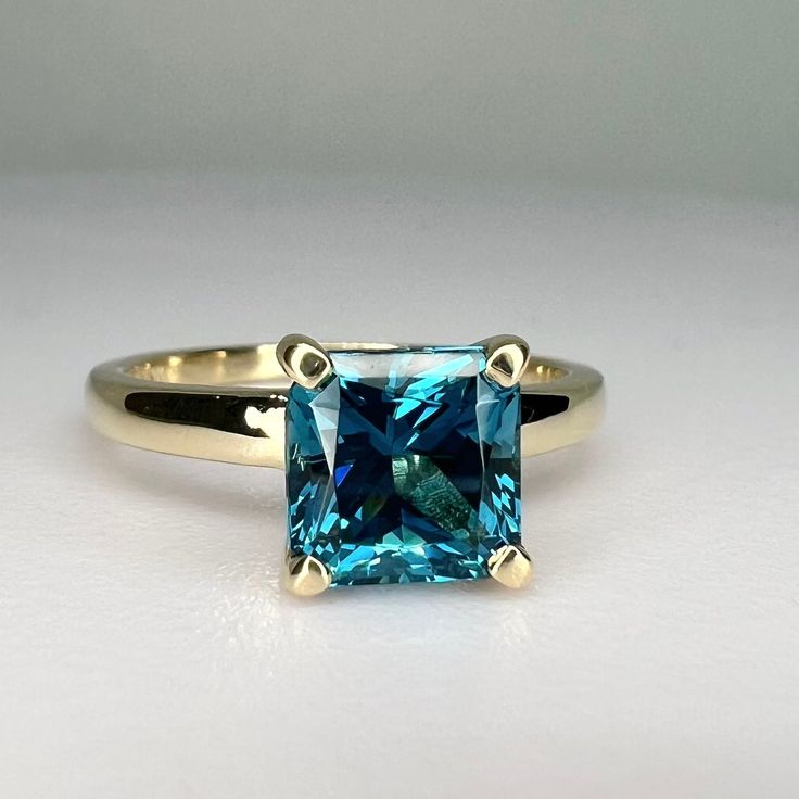 Sleek sellouts! 🤓. Order Blue Radiant Cut Solitaire Engagement Ring With Open U Setting, London Blue Ring, Yellow Gold, Wedding Ring, Gift For Her, #6768 at $429.00 #AnniversaryGift #6768 #GiftForHer #TealGemstone #TealSapphire #LadiesRing #SolitaireEngagement #RadiantCut #14kYellowGold #WeddingRing Blue Solitaire Emerald Promise Ring, Blue Sapphire Solitaire Ring Emerald Cut, Blue Solitaire Sapphire Ring Emerald Cut, Blue Solitaire Emerald Cut Sapphire Ring, Blue Diamond Promise Ring In 14k Gold, Elegant Blue Emerald Ring With Prong Setting, Blue Topaz Diamond Promise Ring, Blue Rings With Prong Setting For Promise, Heirloom Blue Sapphire Solitaire Ring