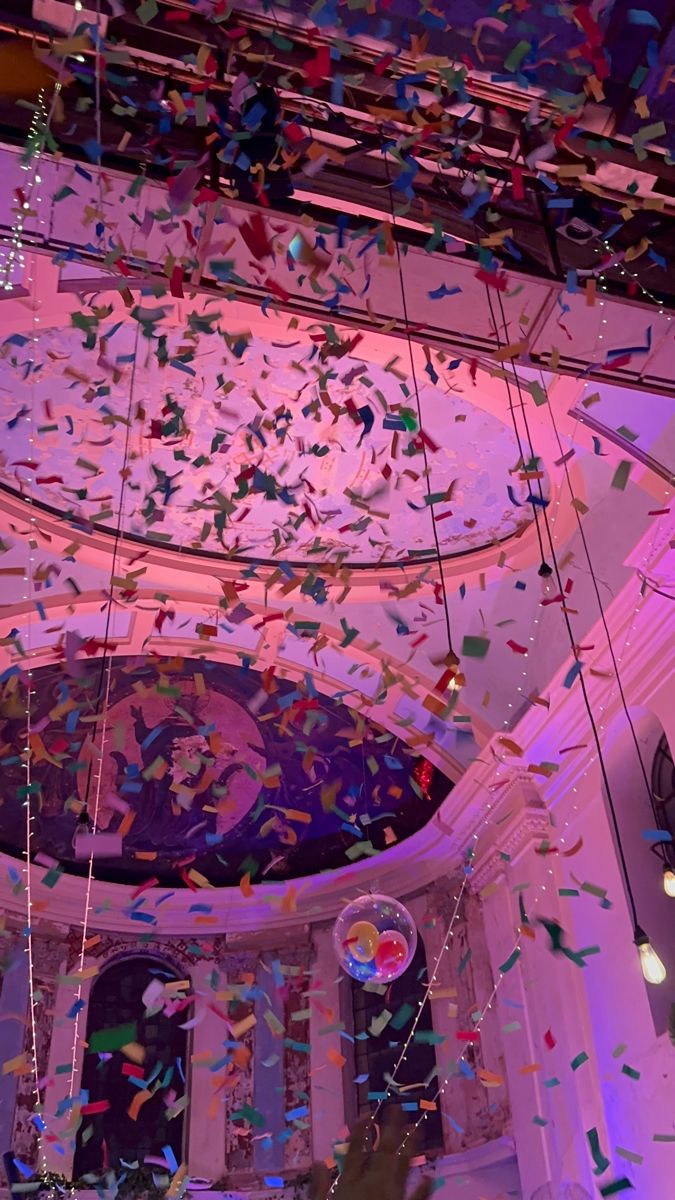 confetti is falling from the ceiling in a room with purple lighting and chandelier